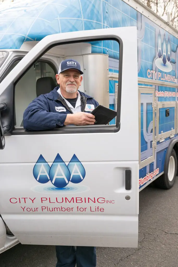 Older Man Standing in Front of Plumbing Truck Door